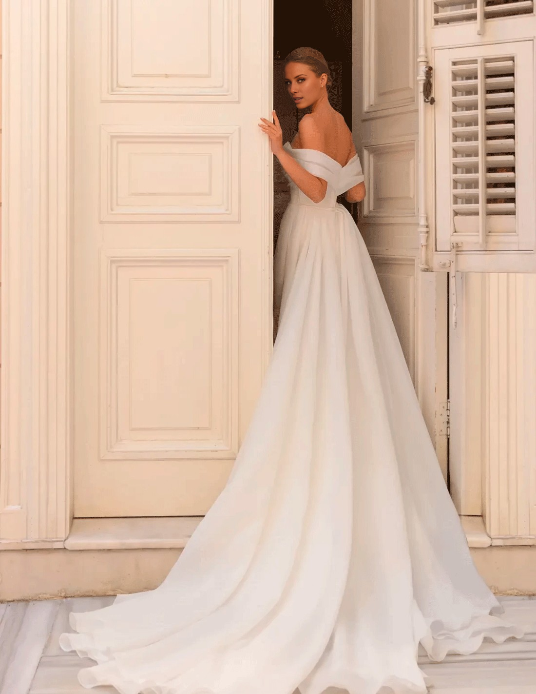Robe de mariée sirène/trompette, épaules dénudées, manches courtes, traîne courte, en mousseline, avec fente sur le devant.