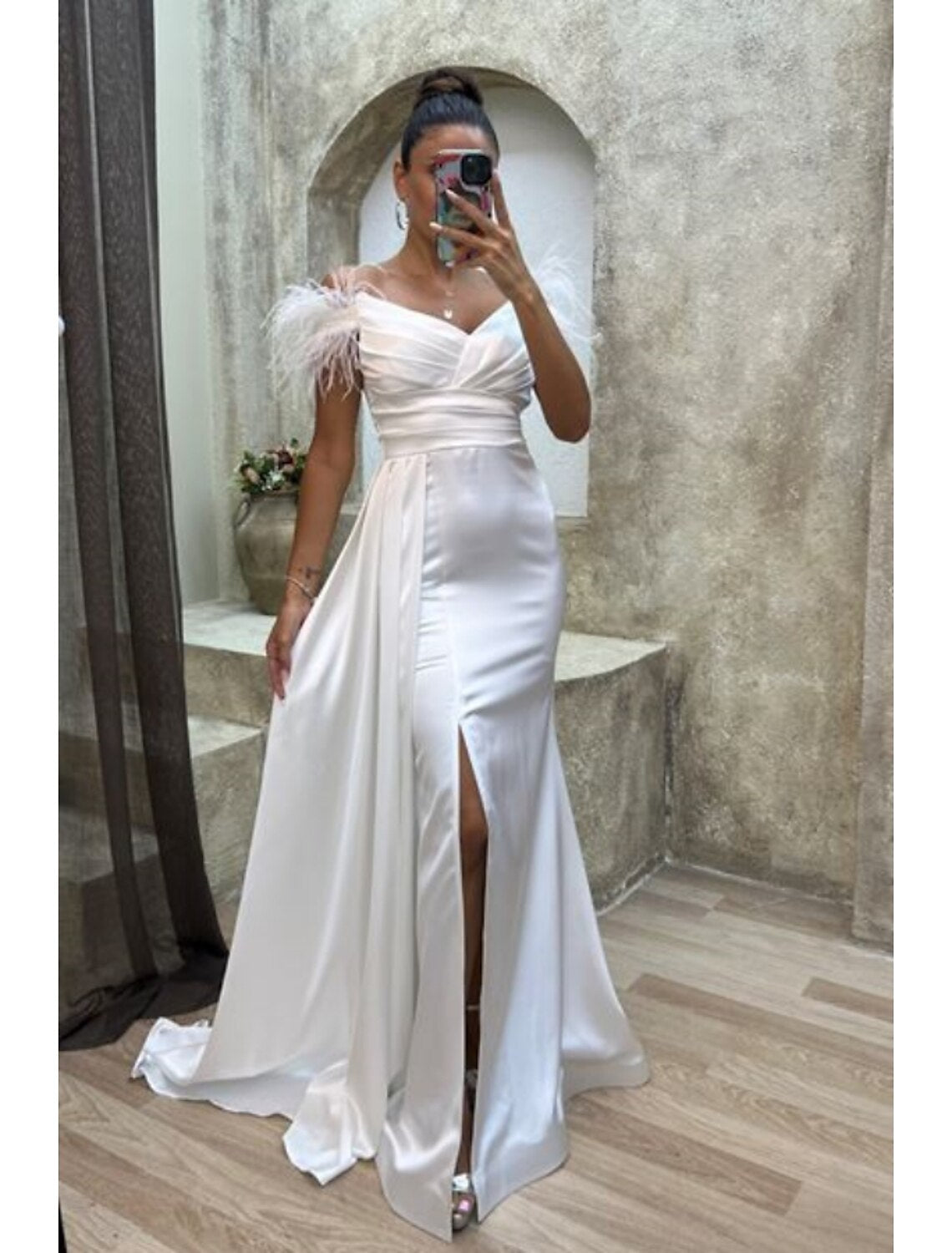 Close-up of the off-shoulder neckline and feather details on the satin gown.