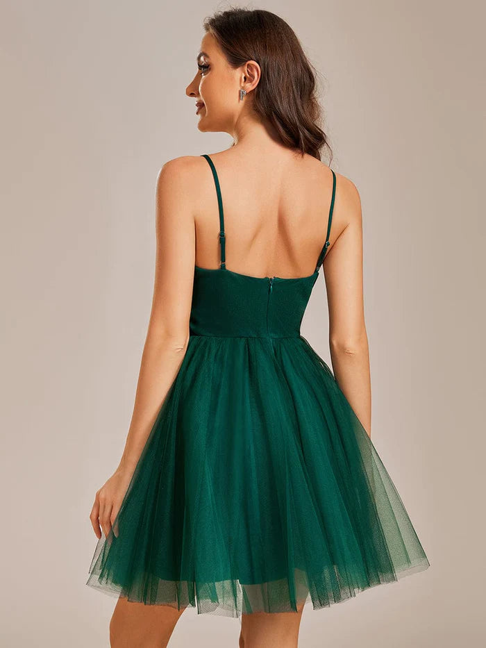 Back view of an elegant dark green tulle short pleated homecoming dress with spaghetti straps.