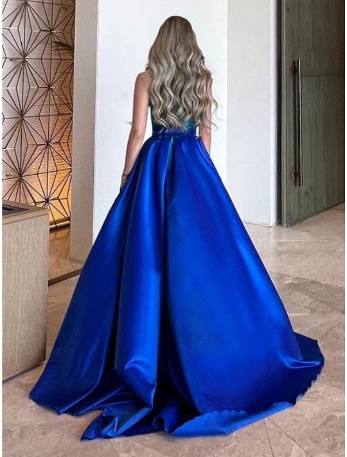 Side view of the elegant navy A-line halter neck satin gown, showcasing delicate pleats.
