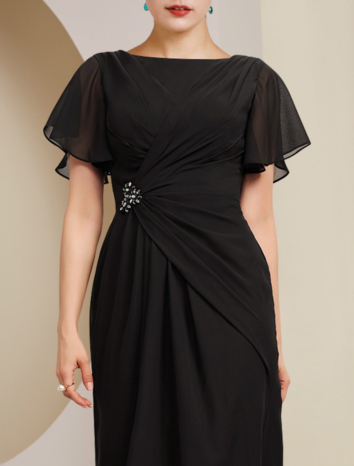 Side view of elegant light blue sheath column dress, highlighting side draping and crystal brooch.