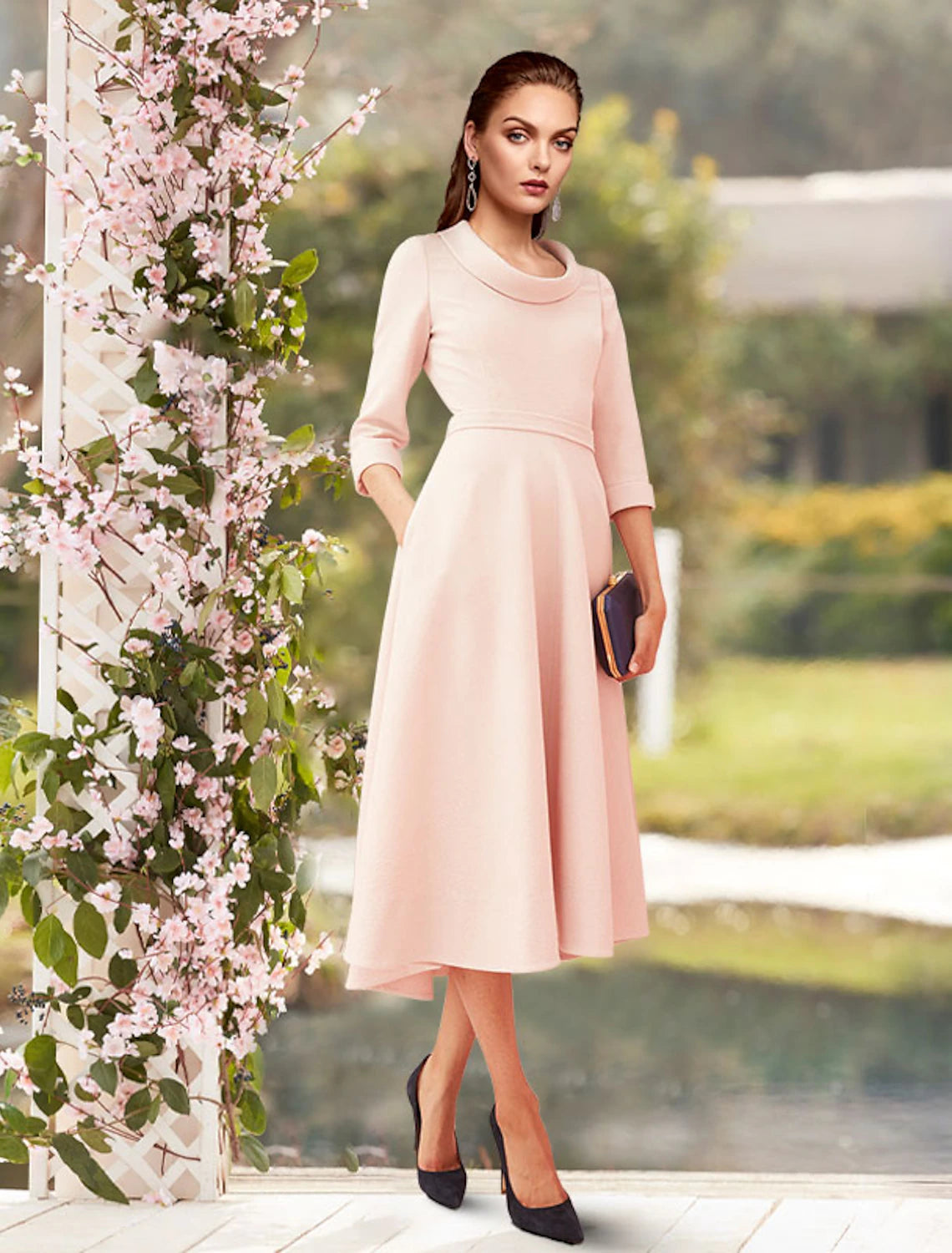 Woman wearing an elegant light-colored sheath Mother of the Bride dress with scoop neck and 3/4 sleeves.