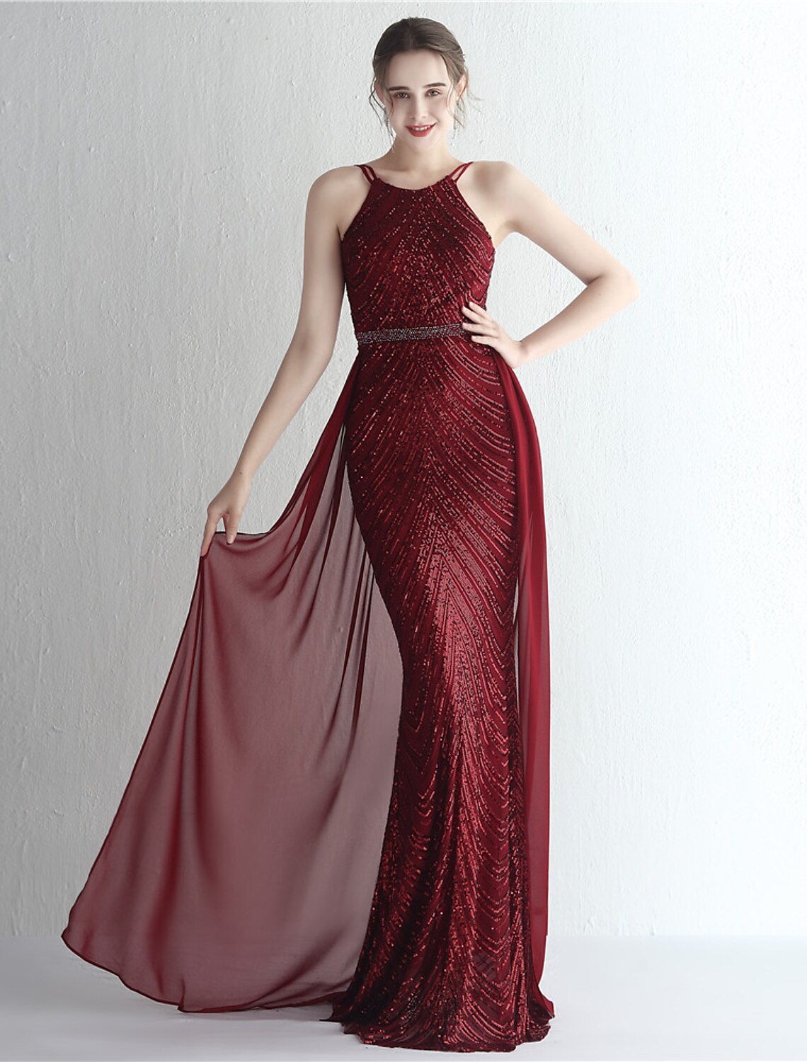 Woman posing elegantly in a sparkling mermaid formal gown.