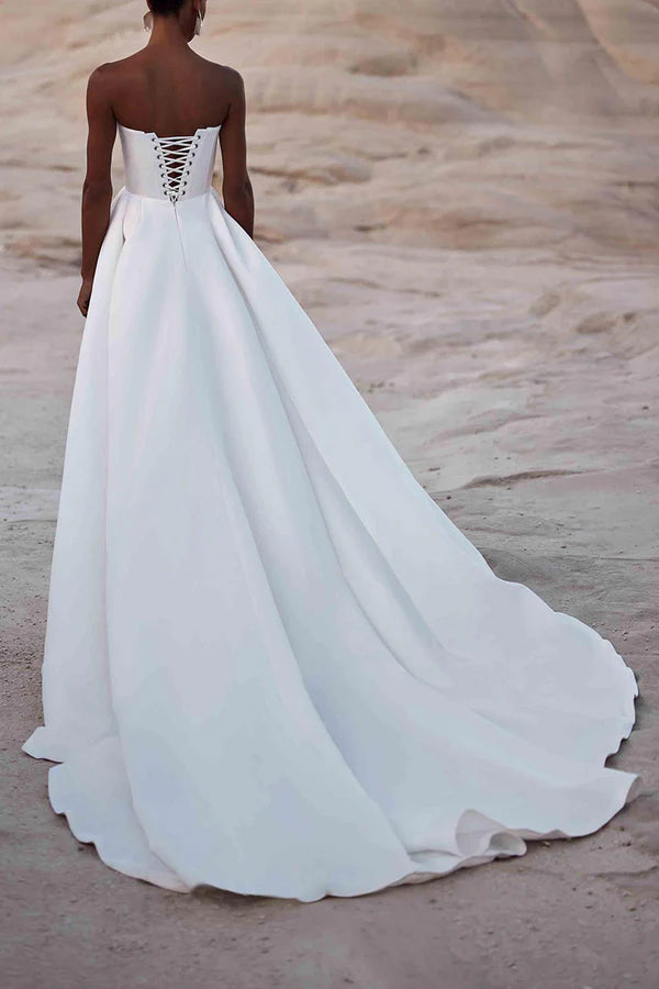Une robe de mariée en satin blanc avec des lignes de traîne de palais et sans bretelles