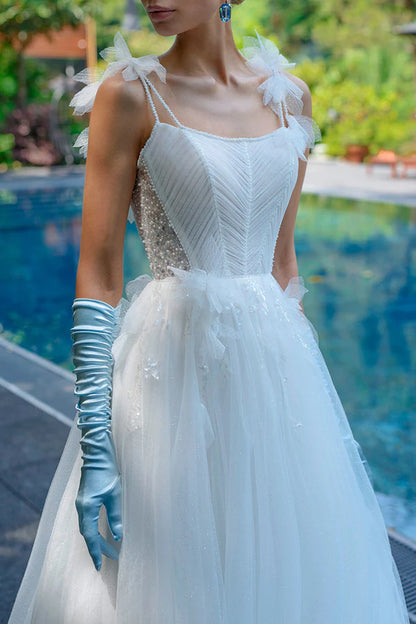 A simple wedding dress with thin shoulder straps, spoonful beads and a single thread